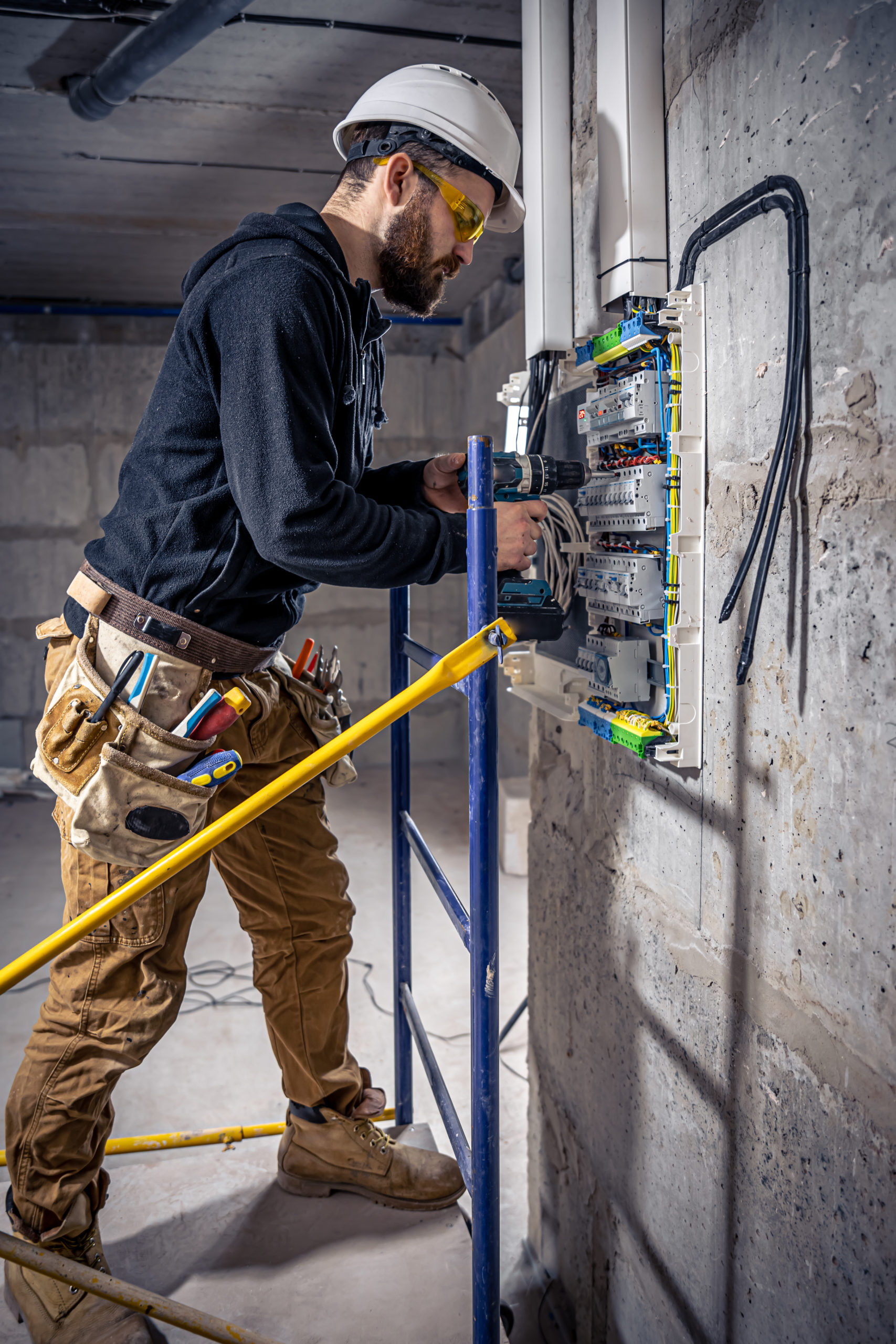 A male electrician works in a switchboard with an electrical connecting cable. electricien masculin travaille dans standard cable raccordement electrique scaled